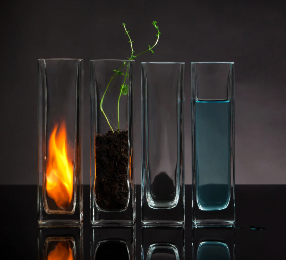 Symboles alchimiques des 4 éléments représentés par feu, terre, air et eau dans des contenants en verre