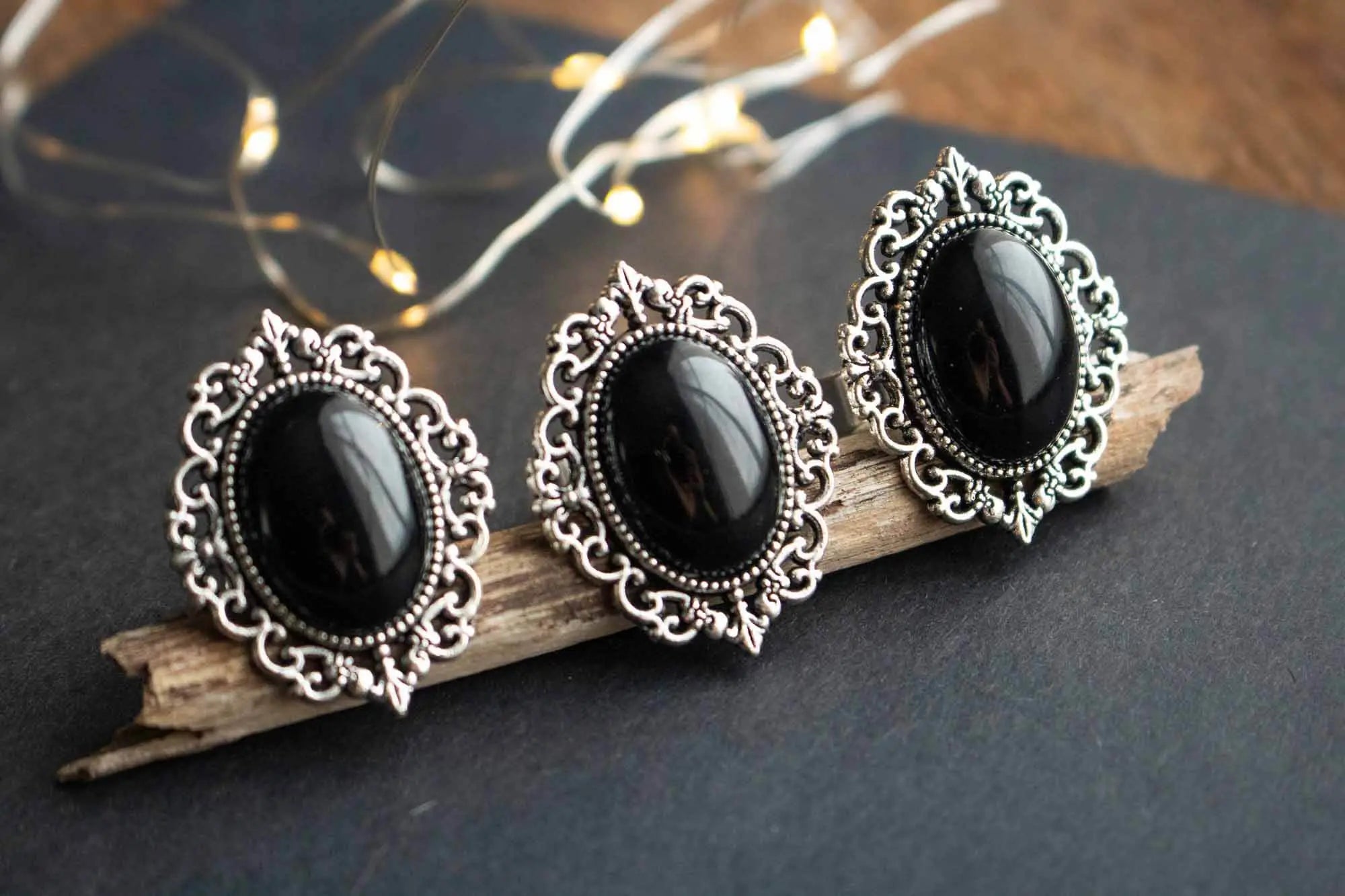 Trois bagues en Onyx noire Hécate ornées de détails en argent sur une base en bois